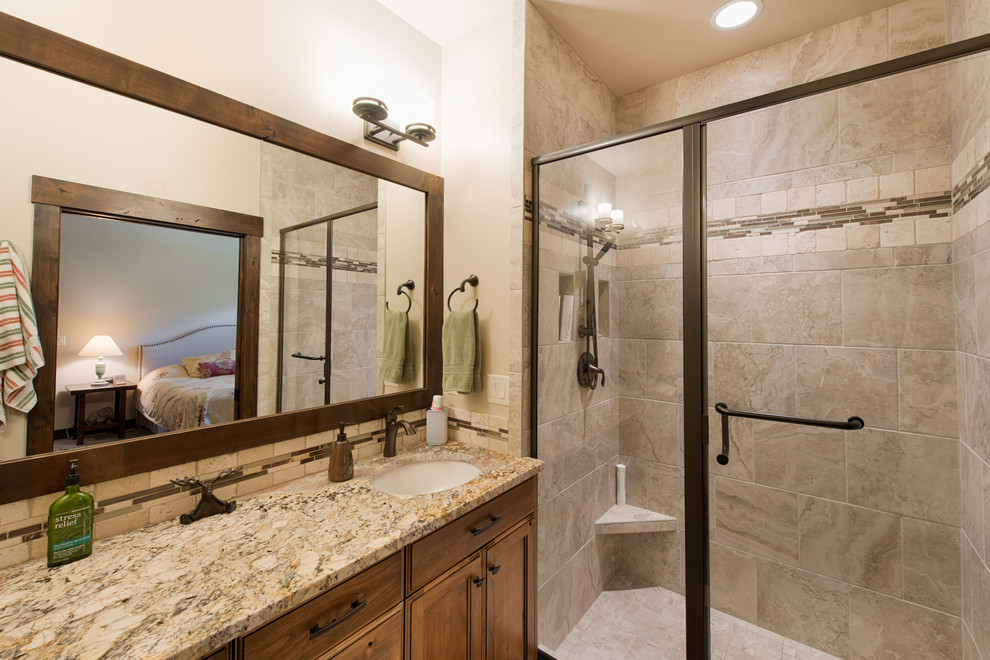 Inspiration for a country master bathroom in Boise with recessed-panel cabinets, brown cabinets, an open shower, beige tile, travertine, beige walls, porcelain floors, an undermount sink, granite benchtops, beige floor and a hinged shower door.