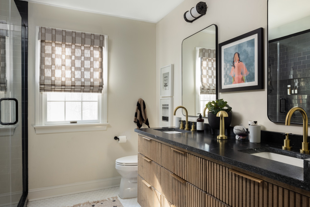This is an example of a medium sized classic family bathroom in Baltimore with light wood cabinets, a corner shower, a one-piece toilet, white tiles, glass sheet walls, white walls, marble flooring, a submerged sink, granite worktops, white floors, a hinged door, black worktops, a shower bench, double sinks, a built in vanity unit and flat-panel cabinets.