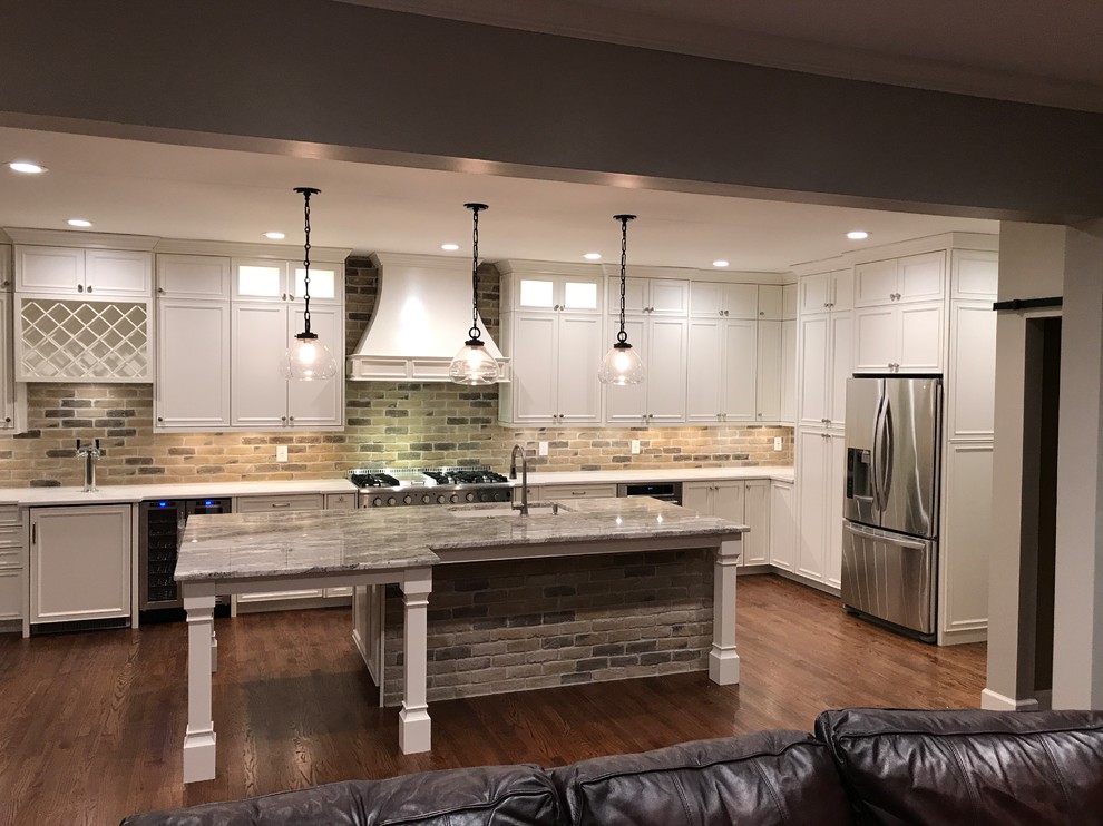 Design ideas for a mid-sized country single-wall kitchen in Atlanta with an undermount sink, beaded inset cabinets, white cabinets, granite benchtops, multi-coloured splashback, brick splashback, white appliances, dark hardwood floors, with island, brown floor and grey benchtop.