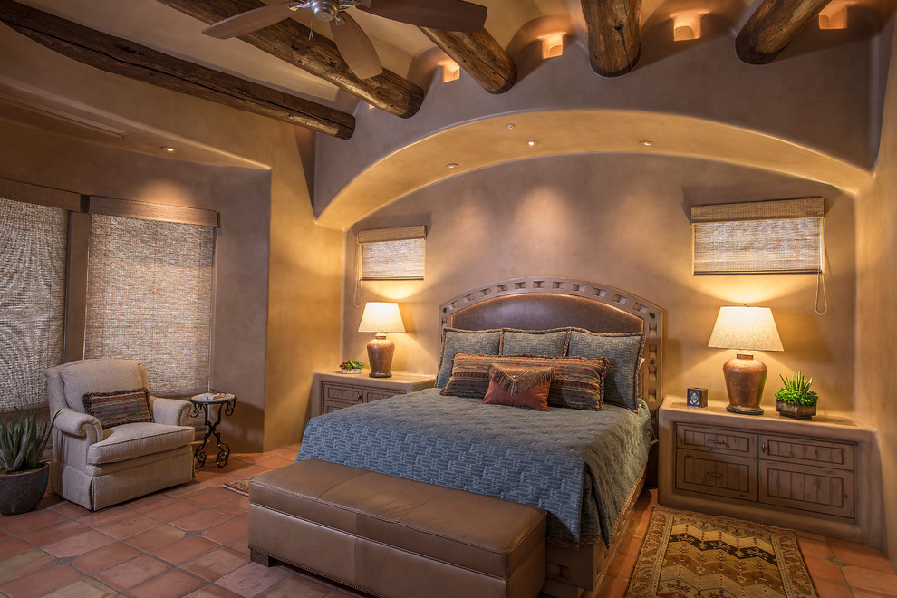 This is an example of a master bedroom in Phoenix with beige walls and terra-cotta floors.