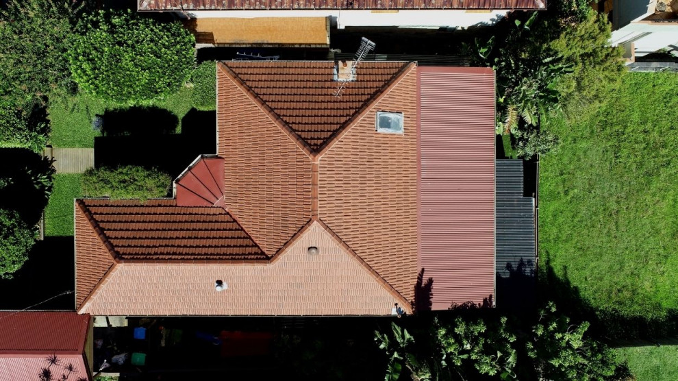 Idée de décoration pour une façade de maison tradition avec un toit à quatre pans, un toit mixte et un toit rouge.