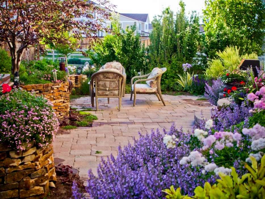 This is an example of a small rustic partial sun backyard concrete paver retaining wall landscape in Denver.