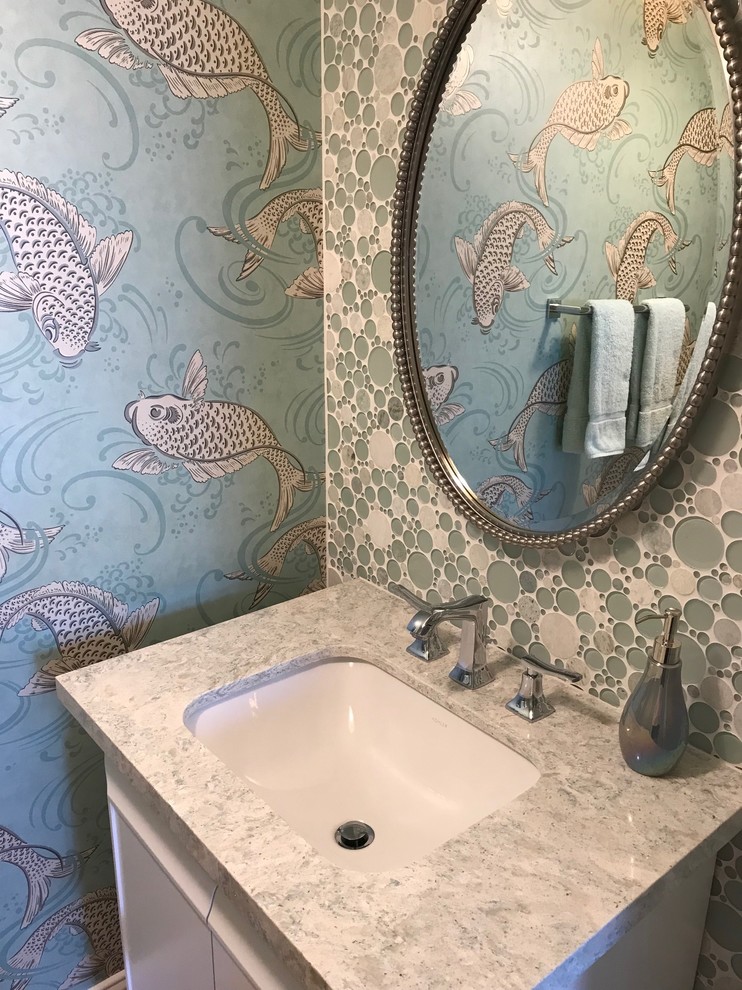 This is an example of a mid-sized beach style powder room in San Francisco with flat-panel cabinets, white cabinets, multi-coloured walls, an undermount sink, granite benchtops and white benchtops.
