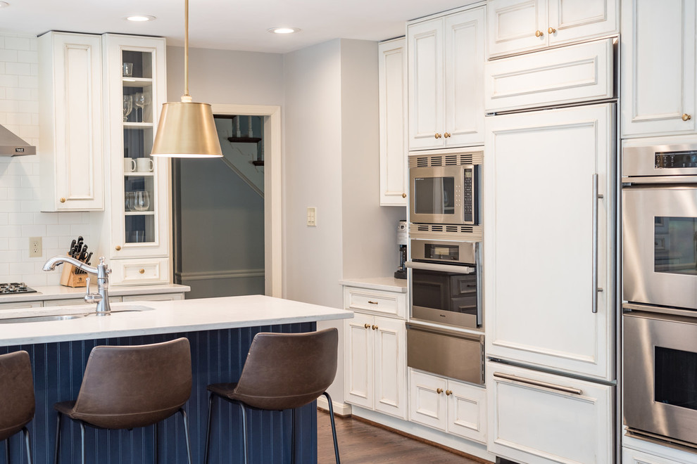 Kitchen - transitional medium tone wood floor and brown floor kitchen idea in DC Metro with an undermount sink, recessed-panel cabinets, white cabinets, granite countertops, white backsplash, subway tile backsplash, stainless steel appliances, an island and white countertops