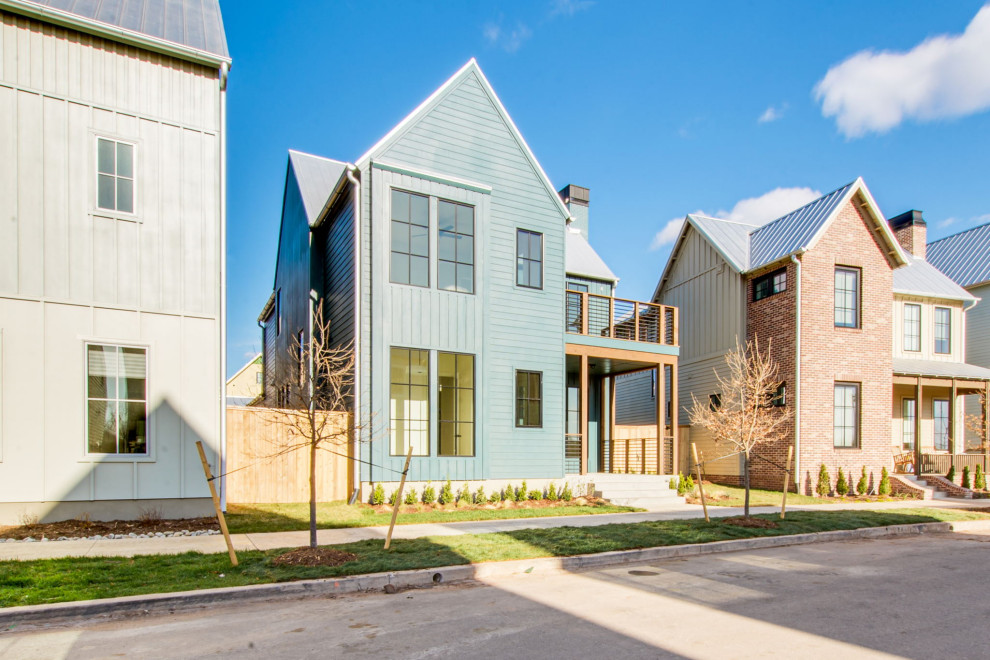 Inspiration för mellanstora lantliga blå hus, med tre eller fler plan, fiberplattor i betong, sadeltak och tak i metall