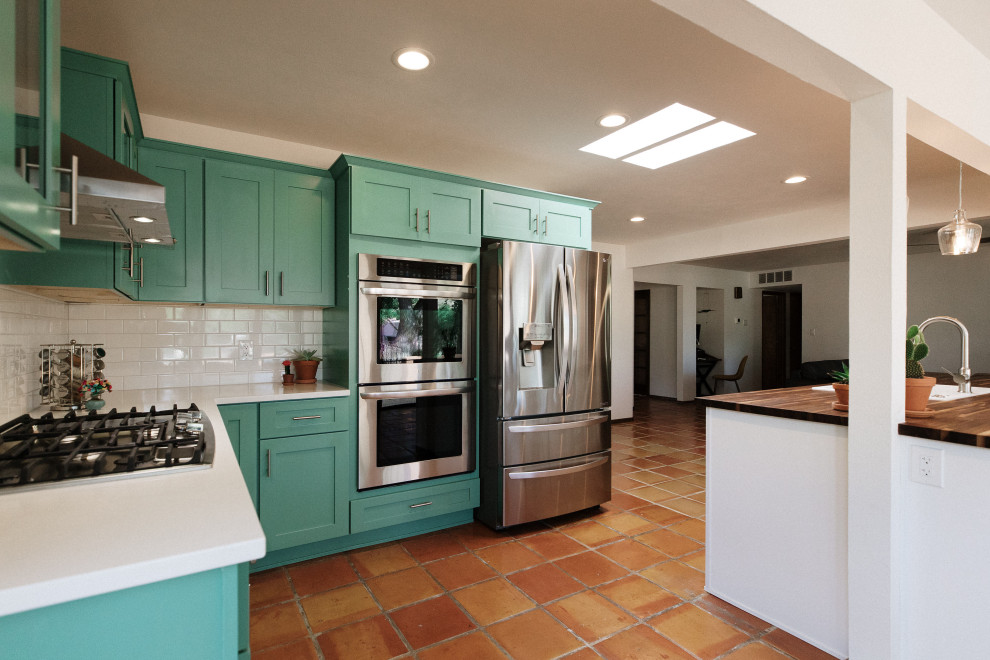 Inspiration for a mid-sized u-shaped eat-in kitchen in Albuquerque with green cabinets, white splashback, subway tile splashback, stainless steel appliances, terra-cotta floors, with island and orange floor.