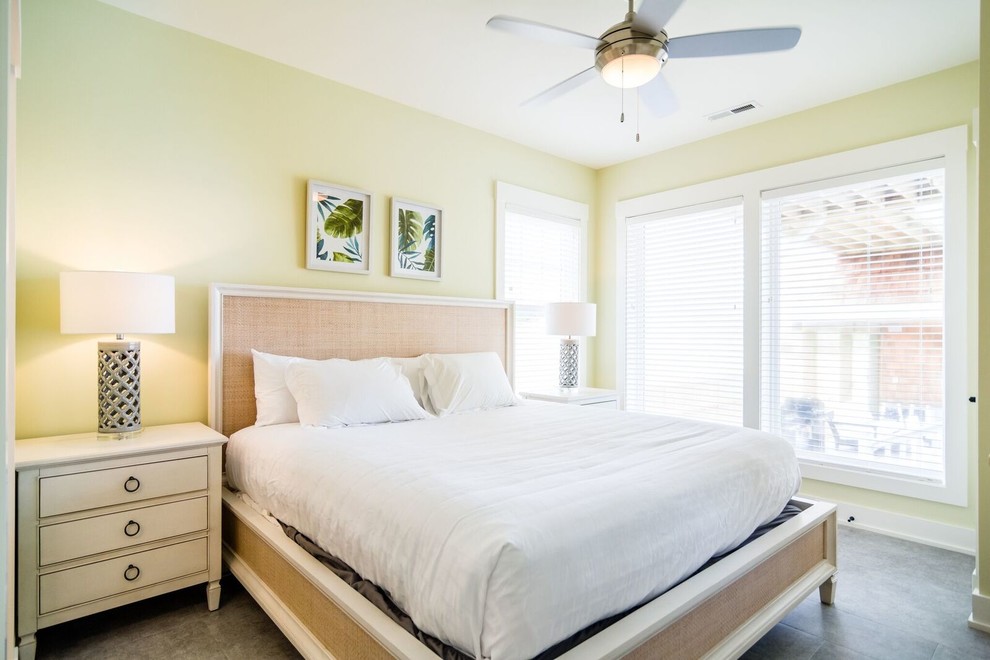 Small beach style guest bedroom in Other with yellow walls, vinyl floors, no fireplace and brown floor.