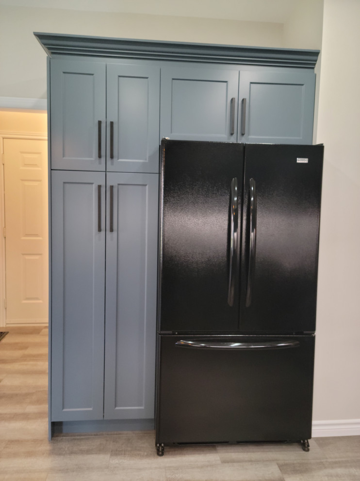 Example of a mid-sized transitional u-shaped vinyl floor eat-in kitchen design with an undermount sink, recessed-panel cabinets, blue cabinets, quartzite countertops, white backsplash, porcelain backsplash, black appliances, a peninsula and black countertops