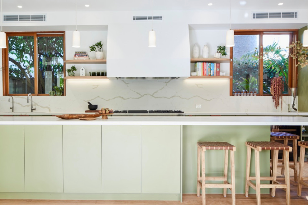 Design ideas for a contemporary galley eat-in kitchen in Sydney with an undermount sink, flat-panel cabinets, green cabinets, solid surface benchtops, white splashback, stone slab splashback, medium hardwood floors, with island and white benchtop.