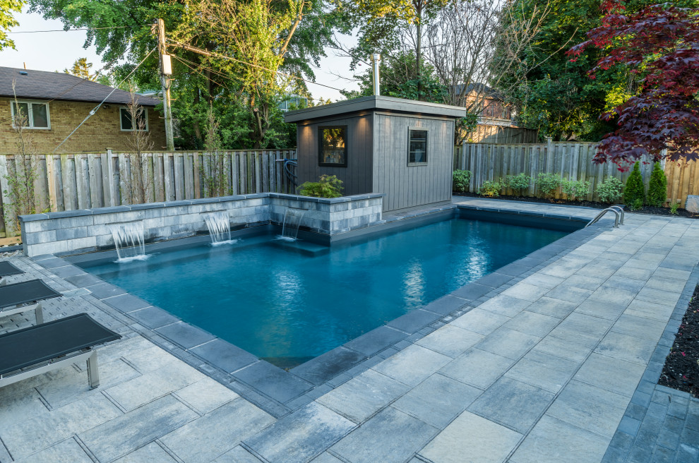 Mid-sized transitional backyard concrete paver and l-shaped lap pool fountain photo in Toronto