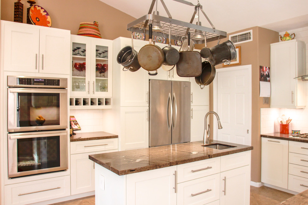 Example of a mid-sized transitional u-shaped porcelain tile and brown floor eat-in kitchen design in Phoenix with an undermount sink, shaker cabinets, white cabinets, white backsplash, subway tile backsplash, stainless steel appliances, an island, granite countertops and brown countertops