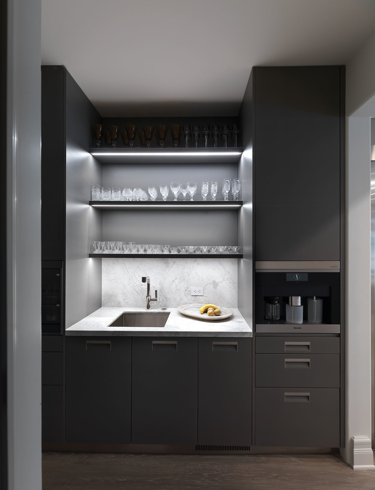 This is an example of a small modern single-wall wet bar in Los Angeles with an undermount sink, flat-panel cabinets, grey cabinets, marble benchtops, grey splashback, marble splashback, dark hardwood floors, brown floor and grey benchtop.