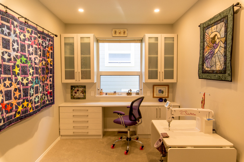 Photo of a mid-sized transitional craft room in Other with beige walls, carpet, a built-in desk and yellow floor.