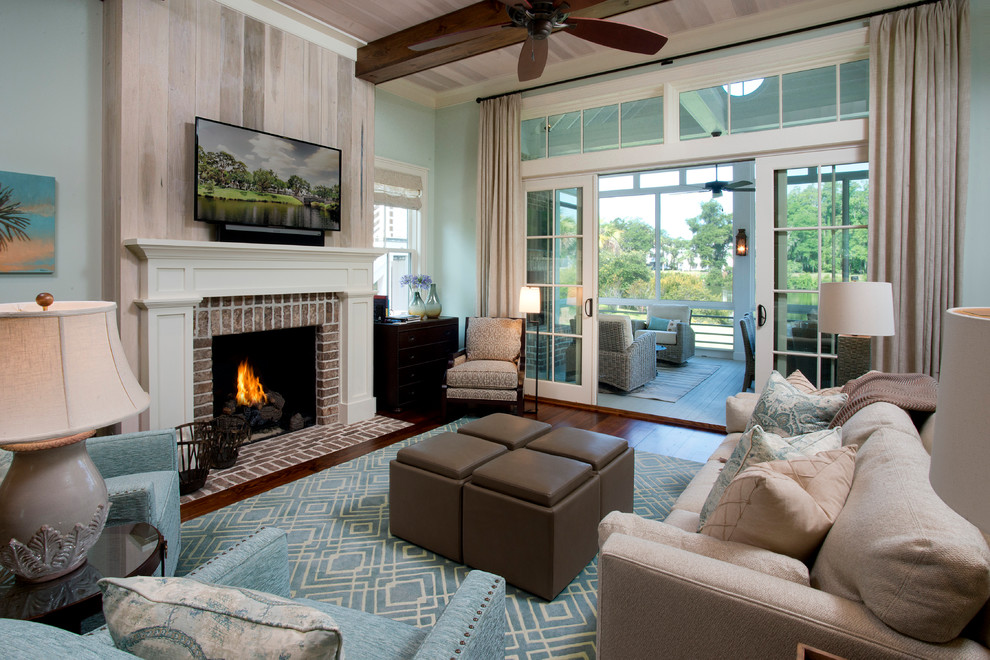 Beach style living room in Atlanta with blue walls, dark hardwood floors, a standard fireplace, a brick fireplace surround, a wall-mounted tv and brown floor.