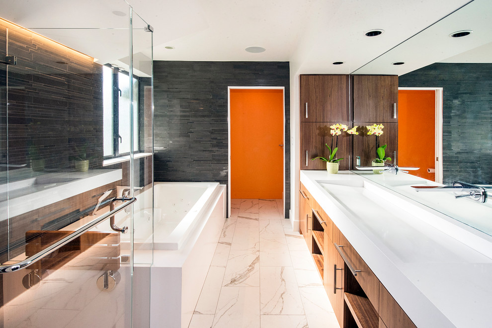 Photo of a large contemporary master bathroom in San Francisco with white floor, a two-piece toilet, grey walls, porcelain floors, a trough sink, an alcove tub, a corner shower, black tile, matchstick tile, white benchtops, dark wood cabinets, solid surface benchtops, a hinged shower door and flat-panel cabinets.