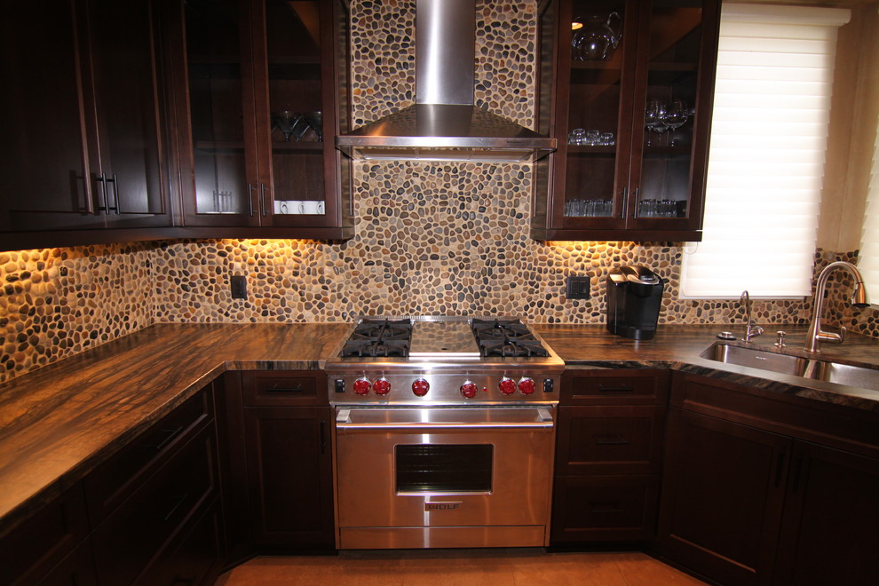 Photo of a mid-sized traditional u-shaped eat-in kitchen in San Diego with a double-bowl sink, glass-front cabinets, dark wood cabinets, granite benchtops, multi-coloured splashback, stainless steel appliances, mosaic tile splashback, medium hardwood floors, a peninsula and brown floor.