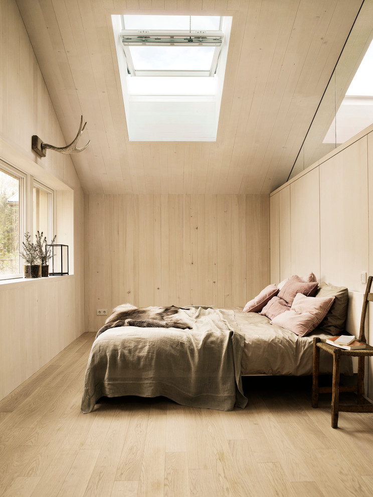 Design ideas for a mid-sized scandinavian master bedroom in Malmo with beige walls and light hardwood floors.