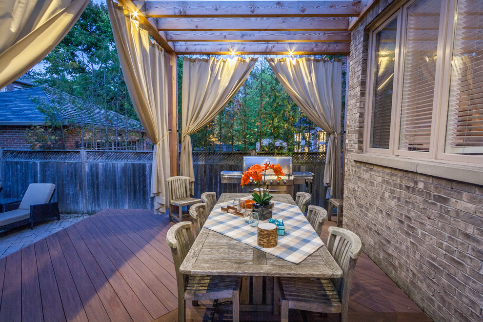Mid-sized transitional backyard deck photo in Toronto with a pergola