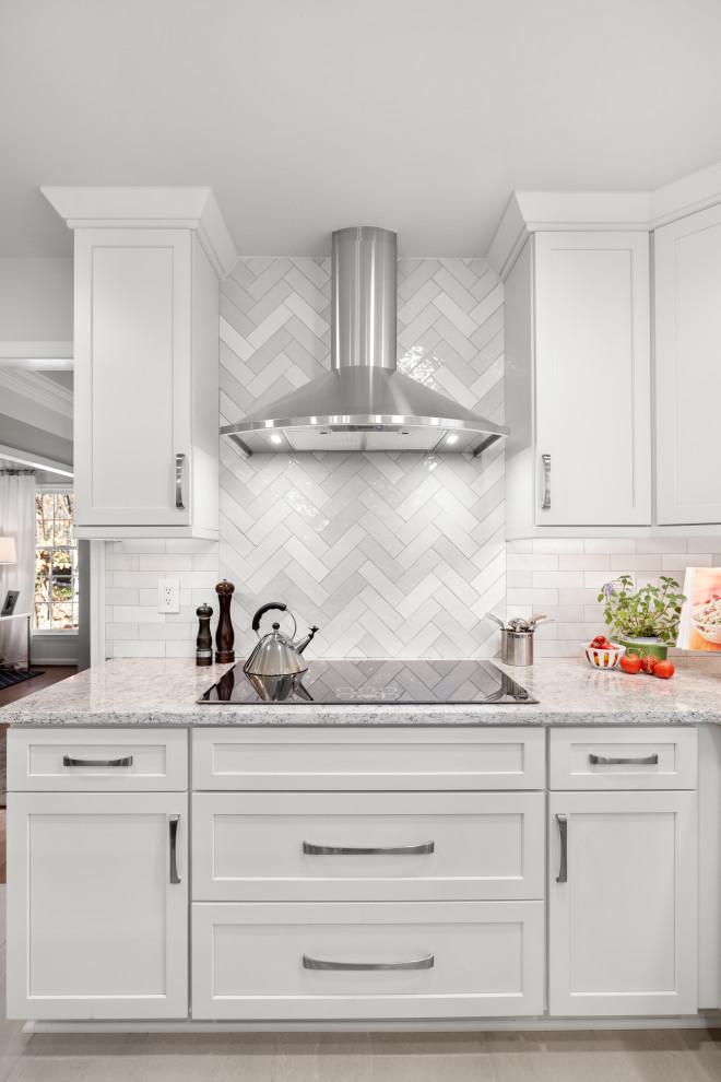 Example of a mid-sized transitional kitchen design in DC Metro with shaker cabinets, white cabinets, quartz countertops, porcelain backsplash, stainless steel appliances and an island