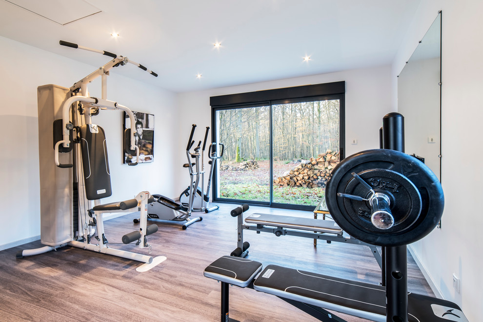 Photo of a mid-sized modern home weight room in Le Havre with white walls and light hardwood floors.