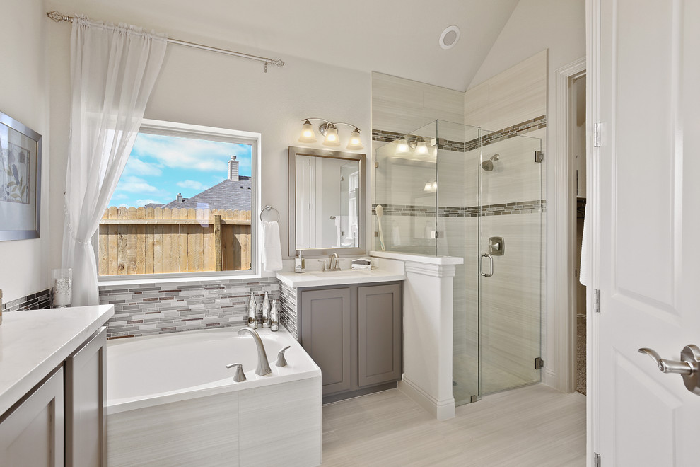 This is an example of a mid-sized contemporary master bathroom in Dallas with shaker cabinets, grey cabinets, a corner tub, a corner shower, beige tile, ceramic tile, beige walls, ceramic floors, an undermount sink, solid surface benchtops, beige floor, a hinged shower door and white benchtops.