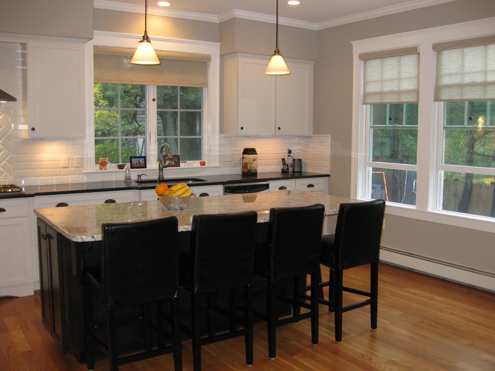Eat-in kitchen - transitional l-shaped medium tone wood floor eat-in kitchen idea in Boston with an undermount sink, shaker cabinets, white cabinets, granite countertops, white backsplash, ceramic backsplash, stainless steel appliances, an island and black countertops
