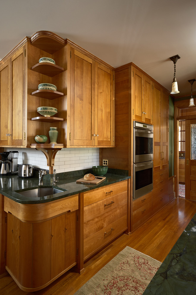 Inspiration for an expansive arts and crafts u-shaped separate kitchen in Minneapolis with an undermount sink, recessed-panel cabinets, medium wood cabinets, granite benchtops, white splashback, subway tile splashback, stainless steel appliances, medium hardwood floors and multiple islands.