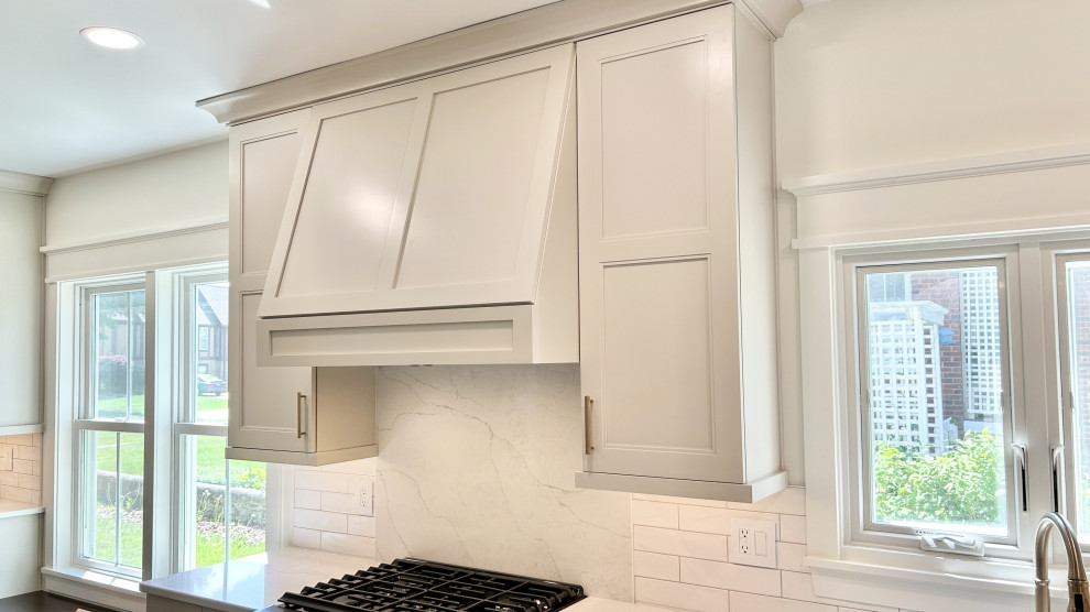 Large transitional u-shaped light wood floor open concept kitchen photo with an undermount sink, flat-panel cabinets, white cabinets, quartz countertops, white backsplash, ceramic backsplash, black appliances, an island and white countertops