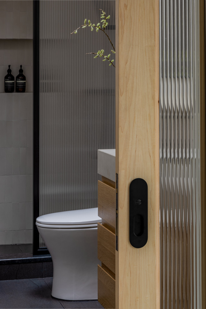 Идея дизайна: маленькая главная ванная комната в стиле неоклассика (современная классика) с плоскими фасадами, светлыми деревянными фасадами, открытым душем, унитазом-моноблоком, бежевыми стенами, полом из сланца, монолитной раковиной, столешницей из бетона, черным полом, шторкой для ванной, серой столешницей, тумбой под две раковины, напольной тумбой и балками на потолке для на участке и в саду