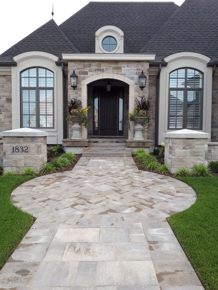 Example of a mid-sized transitional front yard concrete paver front door design with a black front door