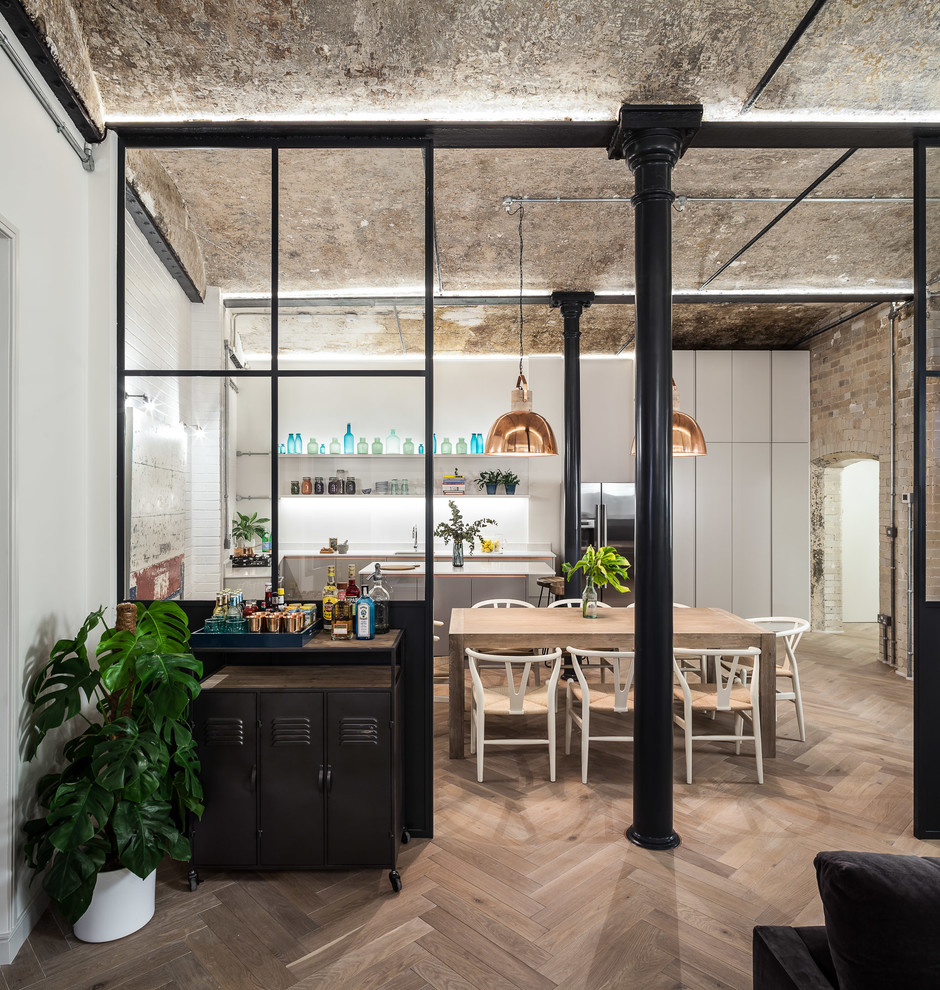 Photo of an industrial open plan dining in London with light hardwood floors.