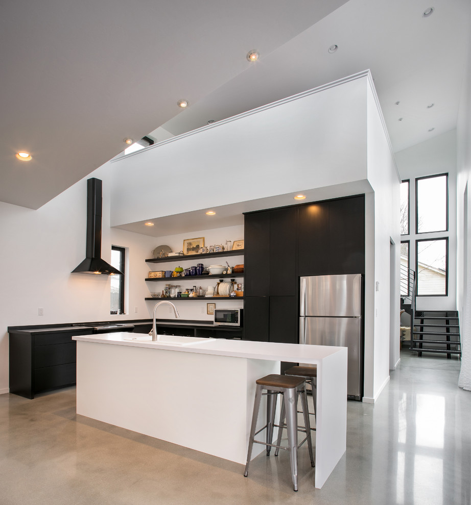 Inspiration for a mid-sized contemporary l-shaped open plan kitchen in Seattle with flat-panel cabinets, laminate benchtops, stainless steel appliances, concrete floors, with island, grey floor, black benchtop, a drop-in sink and black cabinets.