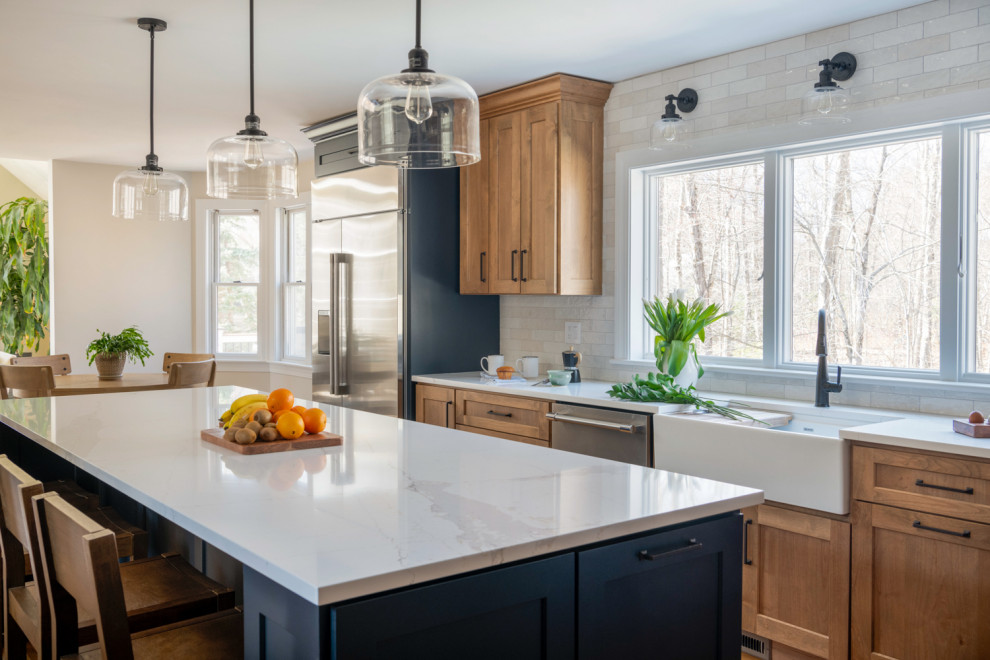 ボストンにある高級な広いトランジショナルスタイルのおしゃれなキッチン (ダブルシンク、シェーカースタイル扉のキャビネット、中間色木目調キャビネット、クオーツストーンカウンター、白いキッチンパネル、磁器タイルのキッチンパネル、シルバーの調理設備、無垢フローリング、青い床、白いキッチンカウンター) の写真