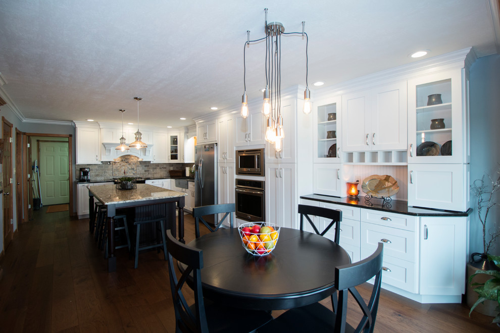Eat-in kitchen - large transitional l-shaped medium tone wood floor eat-in kitchen idea with an undermount sink, shaker cabinets, white cabinets, granite countertops, gray backsplash, stone tile backsplash, stainless steel appliances and an island