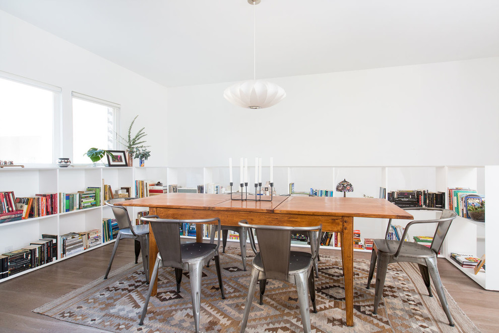 This is an example of a contemporary dining room in Los Angeles with white walls, medium hardwood floors and brown floor.