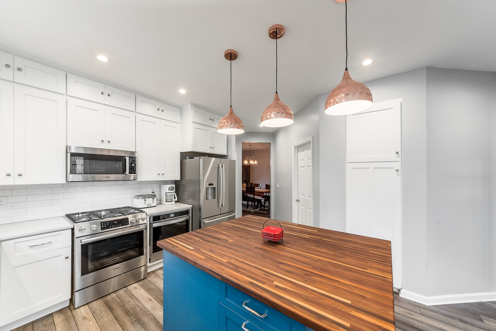 Mid-sized transitional l-shaped eat-in kitchen photo in Columbus with shaker cabinets, quartz countertops, white backsplash, subway tile backsplash and an island