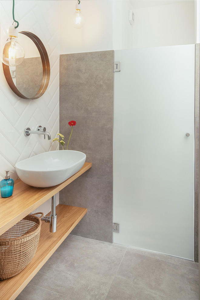 This is an example of an industrial bathroom in Rome with open cabinets, light wood cabinets, white tile, porcelain floors, a vessel sink, wood benchtops, grey floor, ceramic tile, white walls and a hinged shower door.