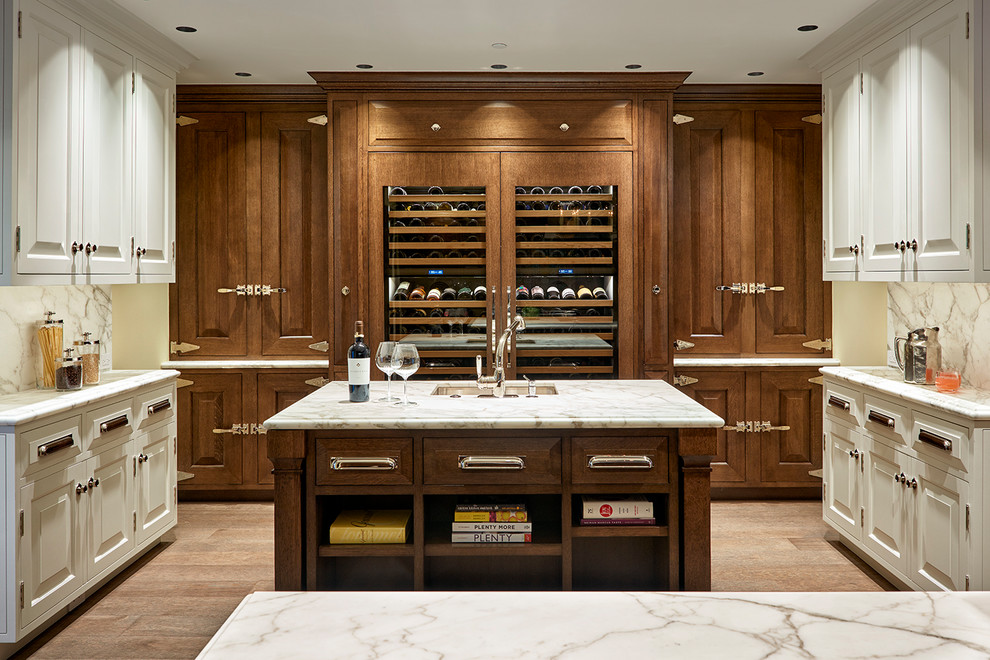 This is an example of a large mediterranean u-shaped open plan kitchen in San Francisco with an undermount sink, raised-panel cabinets, marble benchtops, white splashback, marble splashback, medium hardwood floors, brown floor, white benchtop, medium wood cabinets, panelled appliances and multiple islands.