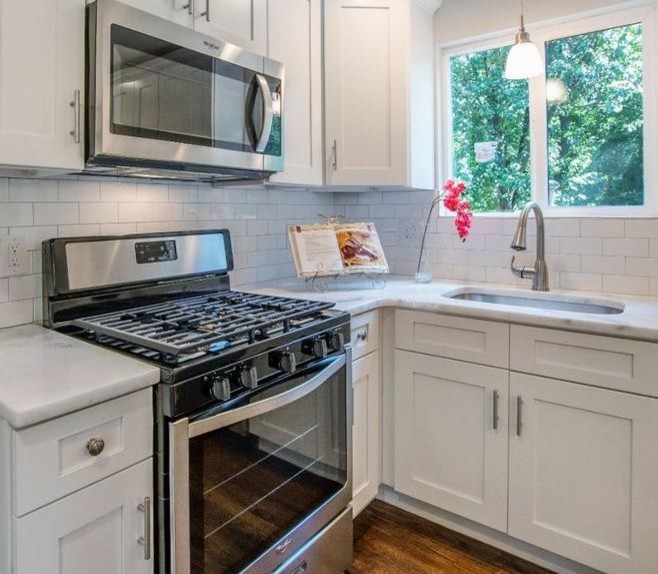This is an example of a mid-sized transitional l-shaped separate kitchen in Philadelphia with an undermount sink, shaker cabinets, white cabinets, marble benchtops, white splashback, ceramic splashback, stainless steel appliances, medium hardwood floors, with island and white benchtop.