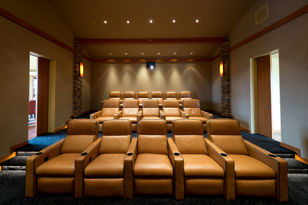 Large country enclosed home theatre in Los Angeles with beige walls, carpet and a projector screen.