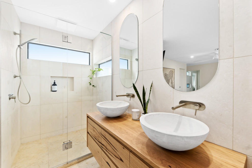 Design ideas for a medium sized nautical ensuite bathroom in Sunshine Coast with light wood cabinets, a freestanding bath, limestone tiles, limestone flooring, an enclosed toilet, double sinks and a floating vanity unit.