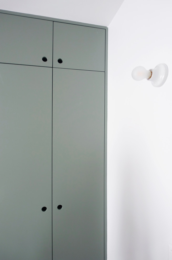 Modelo de armario unisex nórdico pequeño con armarios con rebordes decorativos, puertas de armario verdes, suelo de madera en tonos medios y suelo beige