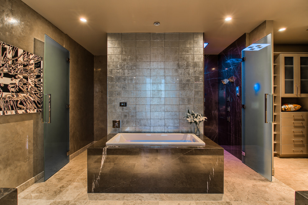 Inspiration for a large contemporary master bathroom in Las Vegas with a drop-in tub, an alcove shower, gray tile, grey walls, granite benchtops, a hinged shower door, limestone floors and beige floor.