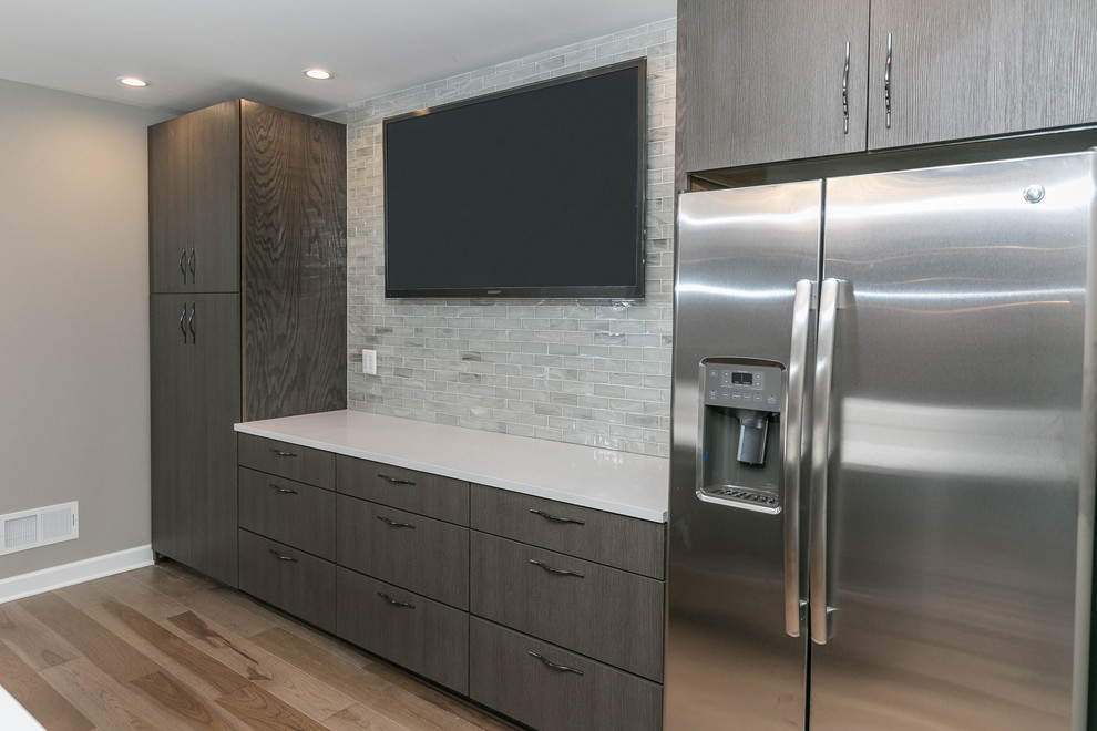 Design ideas for a mid-sized contemporary galley seated home bar in Detroit with an undermount sink, flat-panel cabinets, medium wood cabinets, quartz benchtops, beige splashback, subway tile splashback, light hardwood floors and beige floor.