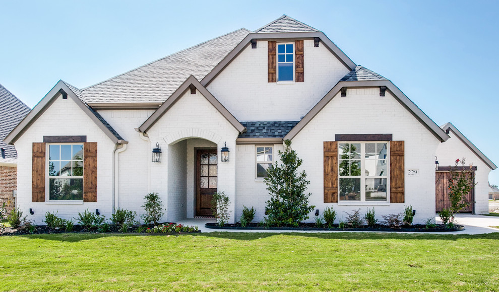 Mid-sized traditional two-storey brick white exterior in Dallas with a clipped gable roof.