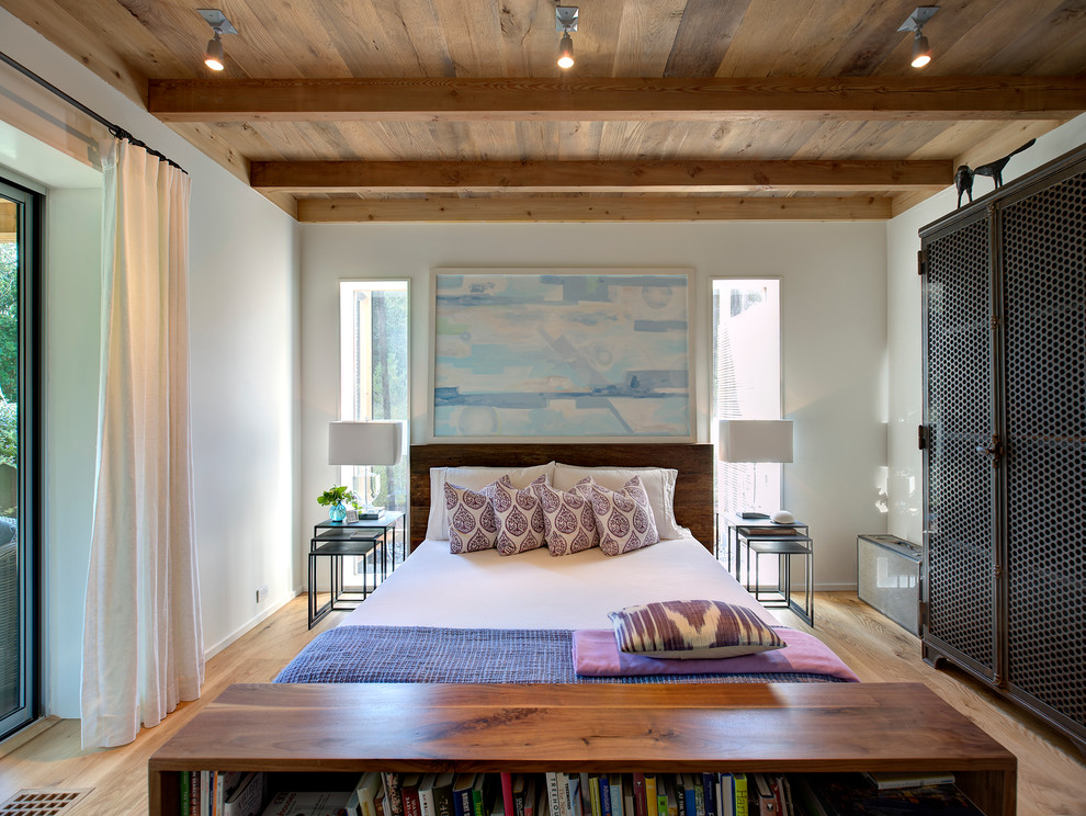 This is an example of a contemporary bedroom in New York with white walls and medium hardwood floors.