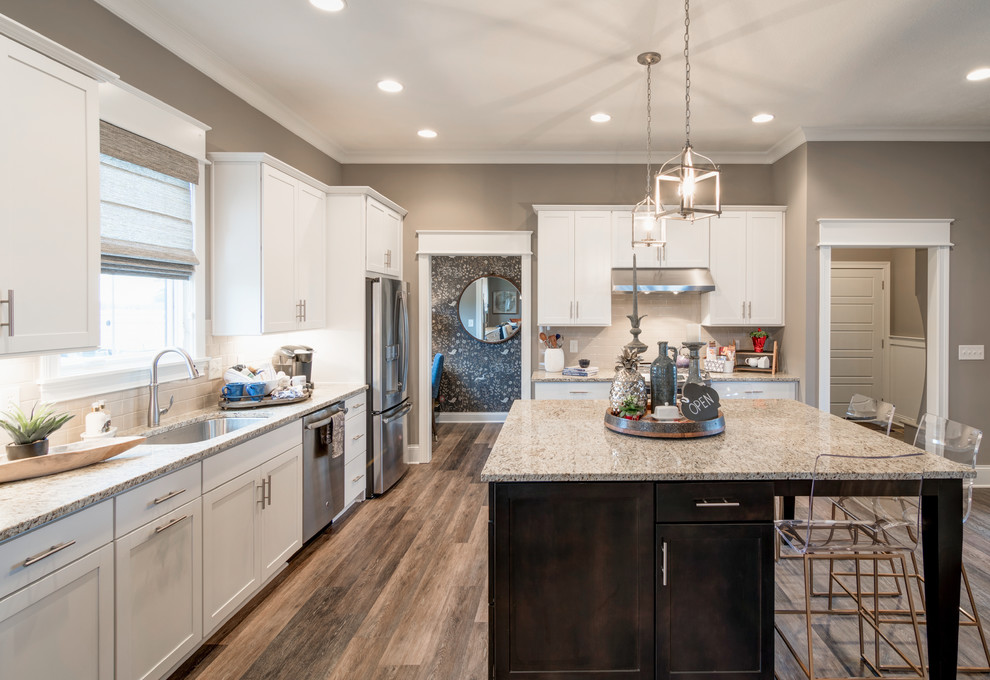 Design ideas for a large arts and crafts single-wall eat-in kitchen in Indianapolis with a single-bowl sink, shaker cabinets, white cabinets, granite benchtops, beige splashback, subway tile splashback, stainless steel appliances, dark hardwood floors and with island.