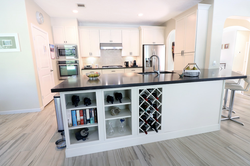 Example of a mid-sized transitional u-shaped porcelain tile and beige floor eat-in kitchen design in Houston with an undermount sink, recessed-panel cabinets, white cabinets, soapstone countertops, white backsplash, subway tile backsplash, stainless steel appliances, an island and black countertops