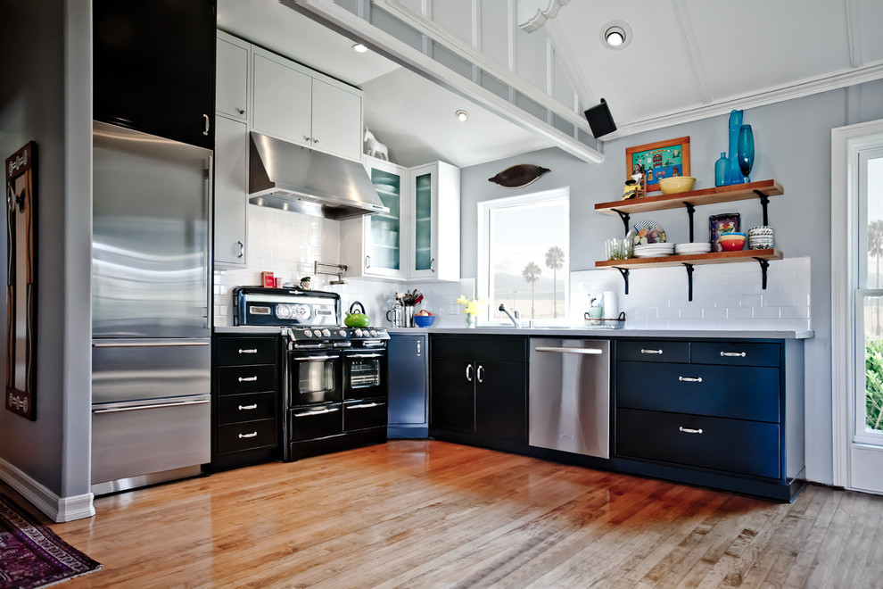 Inspiration for a contemporary l-shaped kitchen in Orange County with black appliances, black cabinets, flat-panel cabinets, white splashback, subway tile splashback and quartz benchtops.