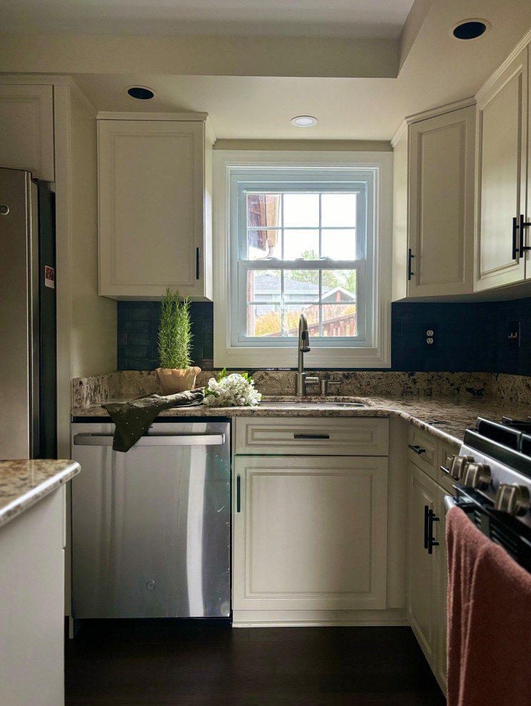 Inspiration for a small contemporary dark wood floor and brown floor kitchen remodel with an undermount sink, shaker cabinets, white cabinets, granite countertops, black backsplash, porcelain backsplash, stainless steel appliances, an island and beige countertops